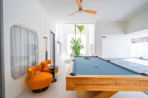 A pool table with a blue felt surface, a wooden table, and orange chairs. - Happy House Pool Villa with KTV near Thepprasit Market   (Pattaya)