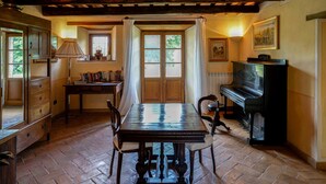 Un coin repas avec une table en bois, des chaises, un piano et une bibliothèque.