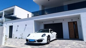 A modern white building with a Porsche parked in front.