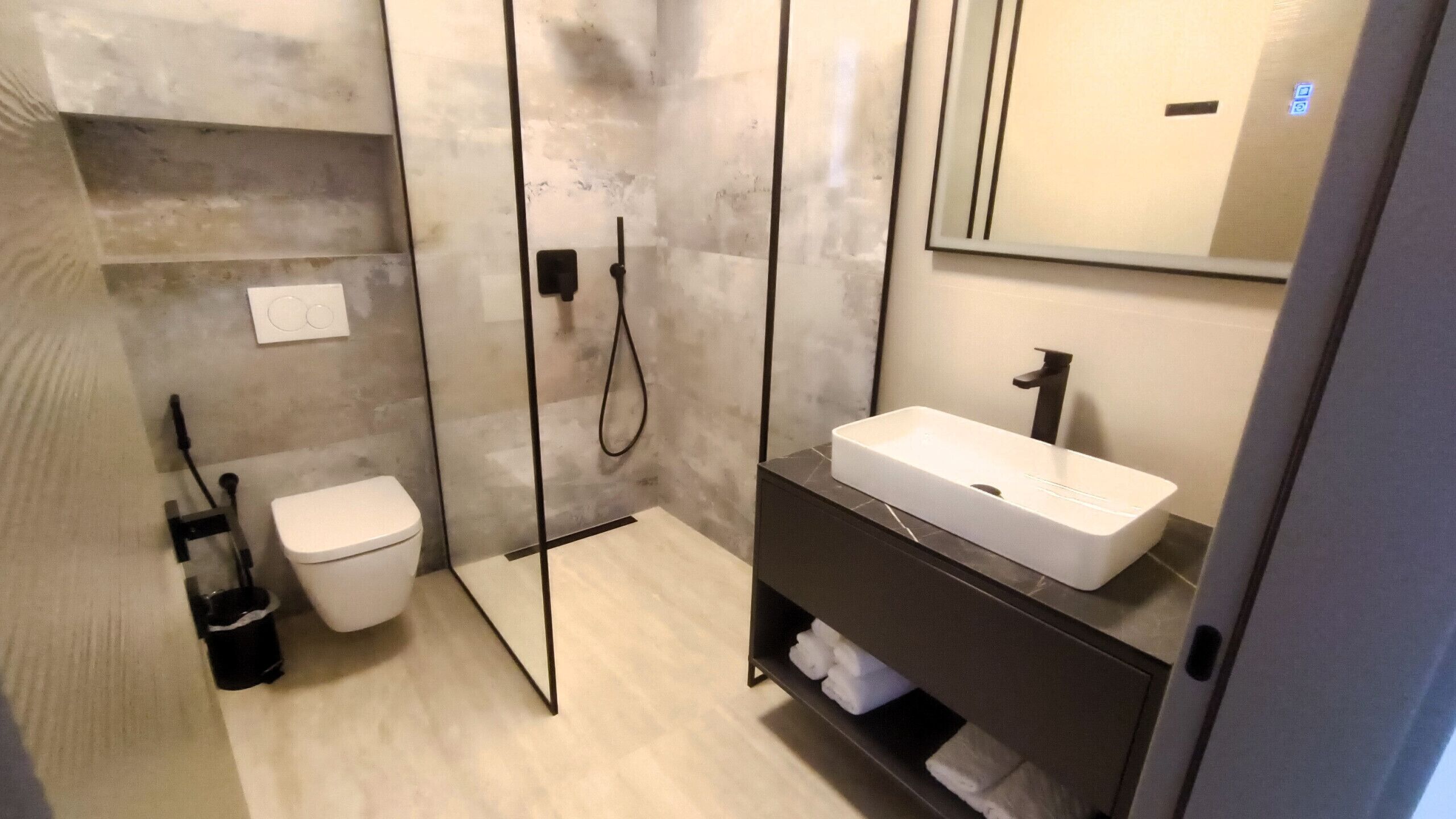 A modern bathroom with a toilet, a shower, and a sink.