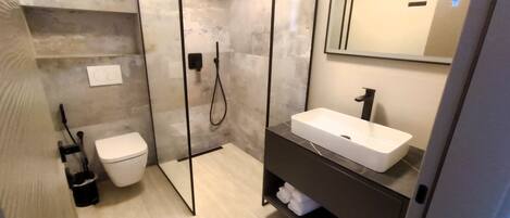 A modern bathroom with a toilet, a shower, and a sink.