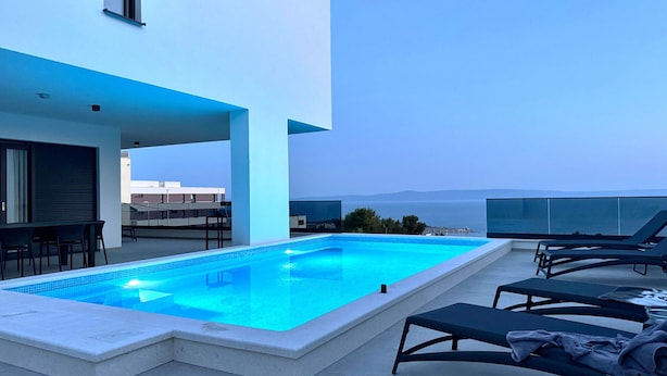 A rooftop pool with lounge chairs and a dining area.
