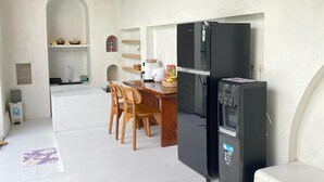A modern kitchen with a dining area, featuring a black refrigerator, a water dispenser, and a wooden dining table with chairs. - Pinnara Borobudur  Private 2 BR Villa  (Borobudur)