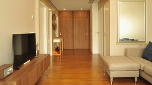 Un salon moderne avec un téléviseur à écran plat posé sur un meuble en bois, un canapé beige et un buffet en bois.