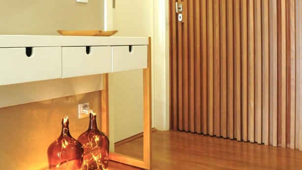 Une salle de bain moderne avec un meuble-lavabo en bois, un miroir rond et deux bouteilles décoratives posées sur le sol.