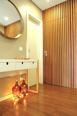 A modern bathroom with a wooden vanity, a round mirror, and two decorative bottles on the floor.
