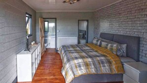 A bedroom with a bed, a nightstand, a dresser, a radiator, and a staircase leading to an upper level. - Paulton - Sleeps 2 - Petfriendly - Hottub - Garden (Bristol)