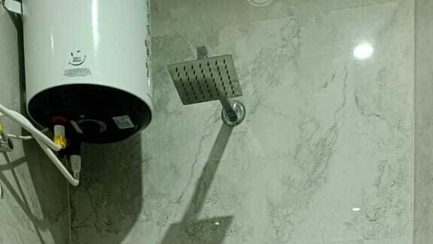 A small bathroom with a toilet, a hand dryer, and a showerhead. - HOTEL RD PALACE (Agra)