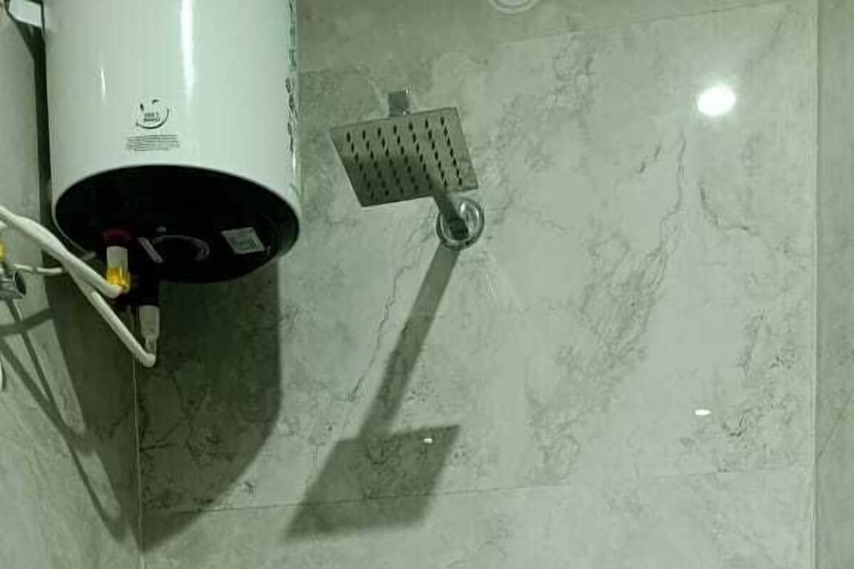 Un baño pequeño con inodoro, secamanos y cabezal de ducha.