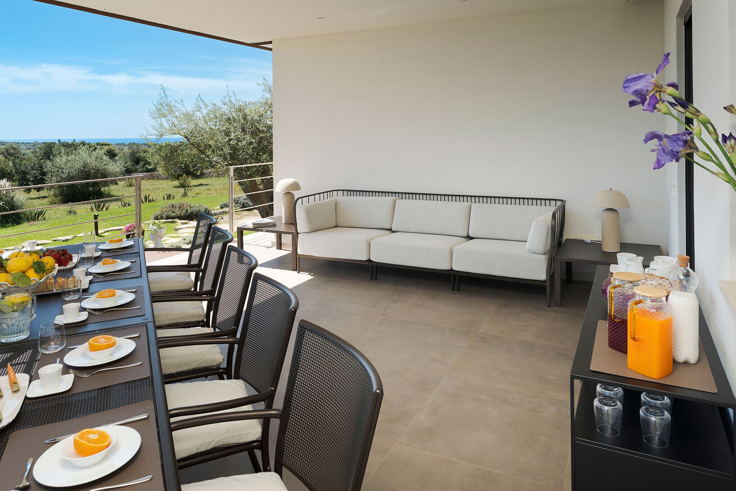 Un espace repas avec une table dressée pour quatre personnes, des sièges à l’extérieur et une vue sur le paysage.