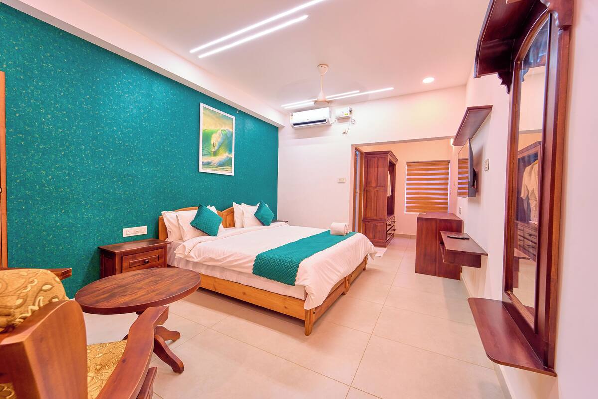 A hotel room with a bed, bedside table, chair, and a small desk with a mirror.