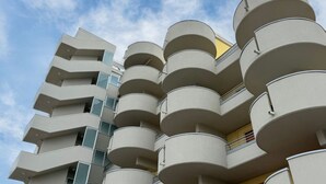 A multi-story building with balconies, a clear sky, and a yellow door. - SE164 - Marotta, Three-Room Apartment with Sea View and Terrace (Marotta)