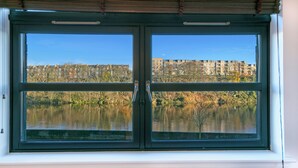Ett fönster med utsikt över en sjö och byggnader i bakgrunden.