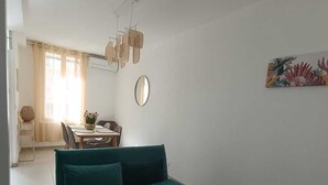 A living room with a teal sofa, a wooden coffee table, and a dining area with a table and chairs. - Bright cocoon with private courtyard (Salses-le-Château)