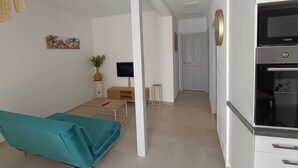 A modern kitchen with a built-in oven and a dining area with a teal sofa. - Bright cocoon with private courtyard (Salses-le-Château)