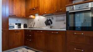 Una cocina con armarios de madera, horno empotrado y salpicadero de azulejos.