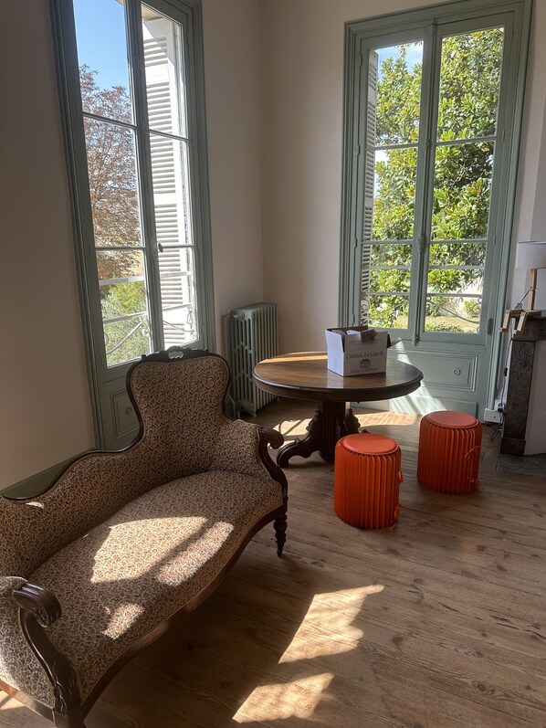 A room with a leopard print sofa, a round wooden table, and two orange stools.