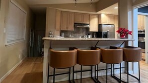 A modern kitchen with a central island, bar stools, and stainless steel appliances.