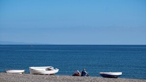 A pebbled beach with several small boats moored along the shore. - Anna del Mar | Coastal Boho (San Luis de Sabinillas)