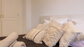 A neatly made bed with multiple pillows and a folded blanket on a dark woven bedspread. - Anna del Mar | Coastal Boho (San Luis de Sabinillas)