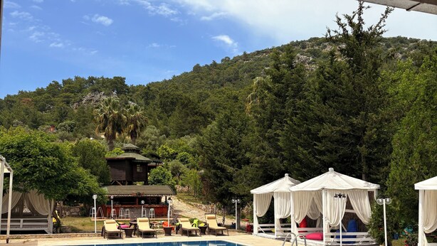 A swimming pool with a tiled deck, lounge chairs, and a gazebo. - Olympos Talara (Kumluca)