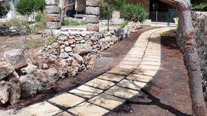 A stone pathway leading to a building with a stone wall on one side.