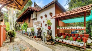 Un edificio tradicional con techo de tejas, plantas en macetas y un sendero que lleva a la entrada.