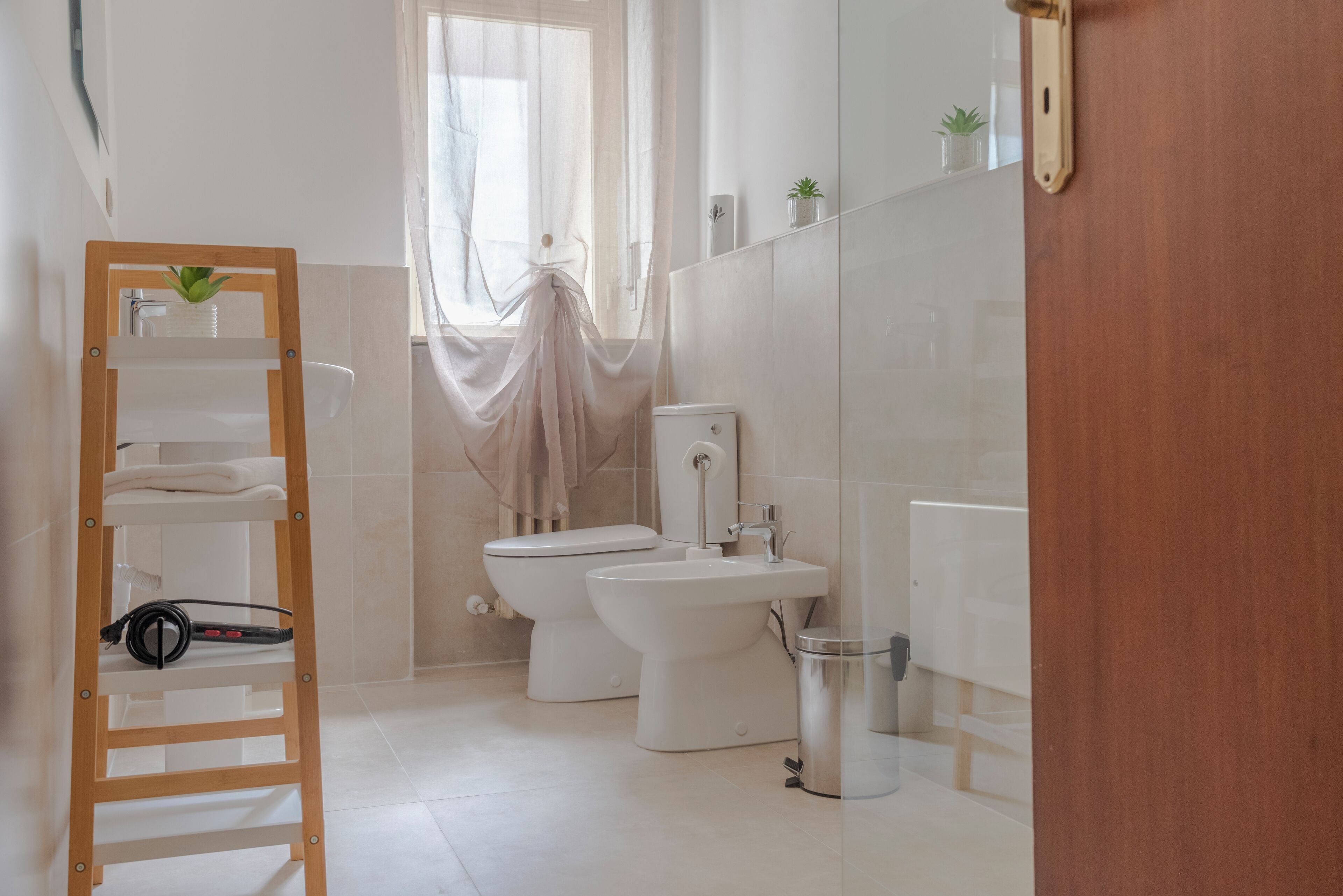 Ein modernes Badezimmer mit einer Holzleiter, einer Toilette, einem Bidet und einem Mülleimer.