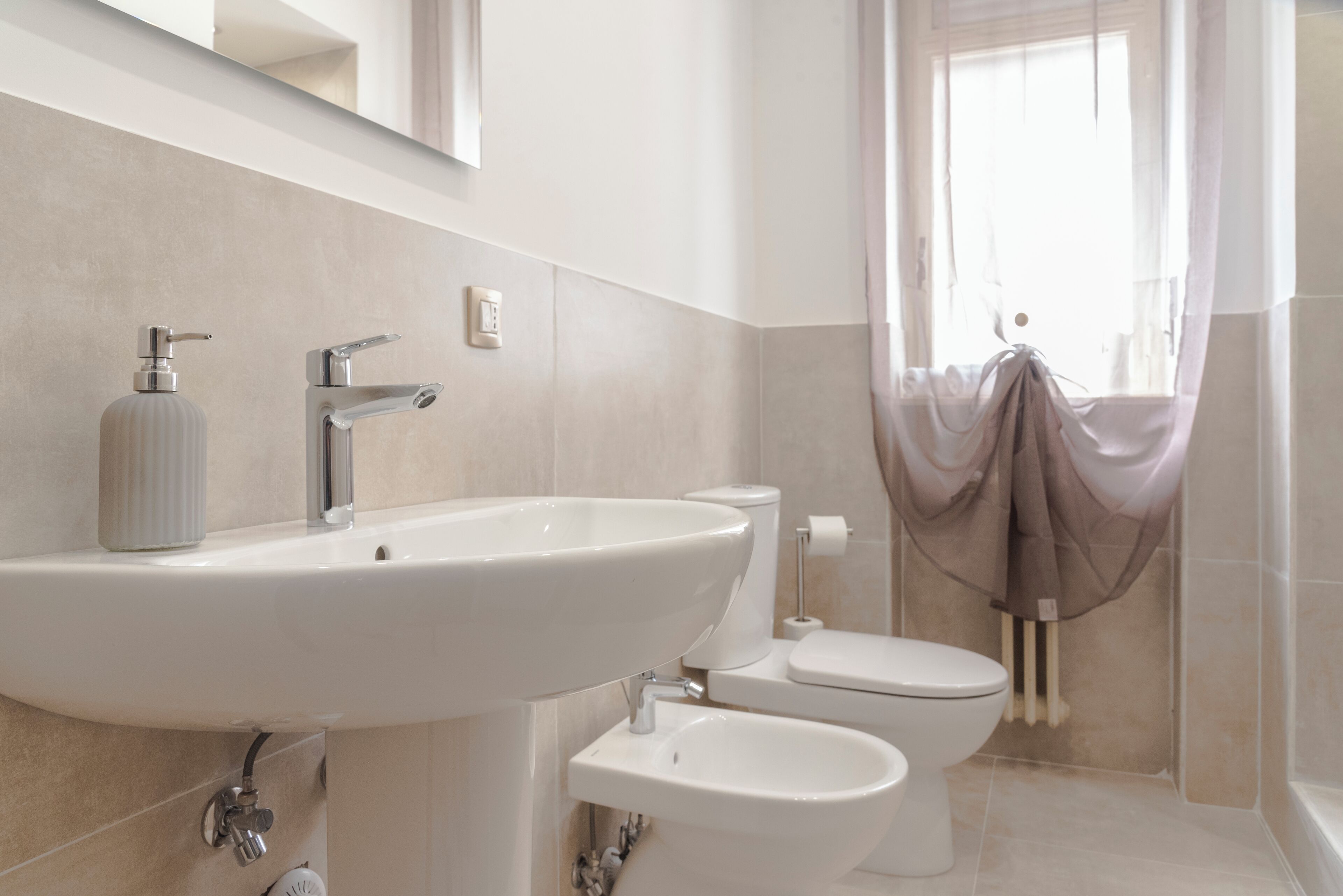 A bathroom with a sink, toilet, and bidet.