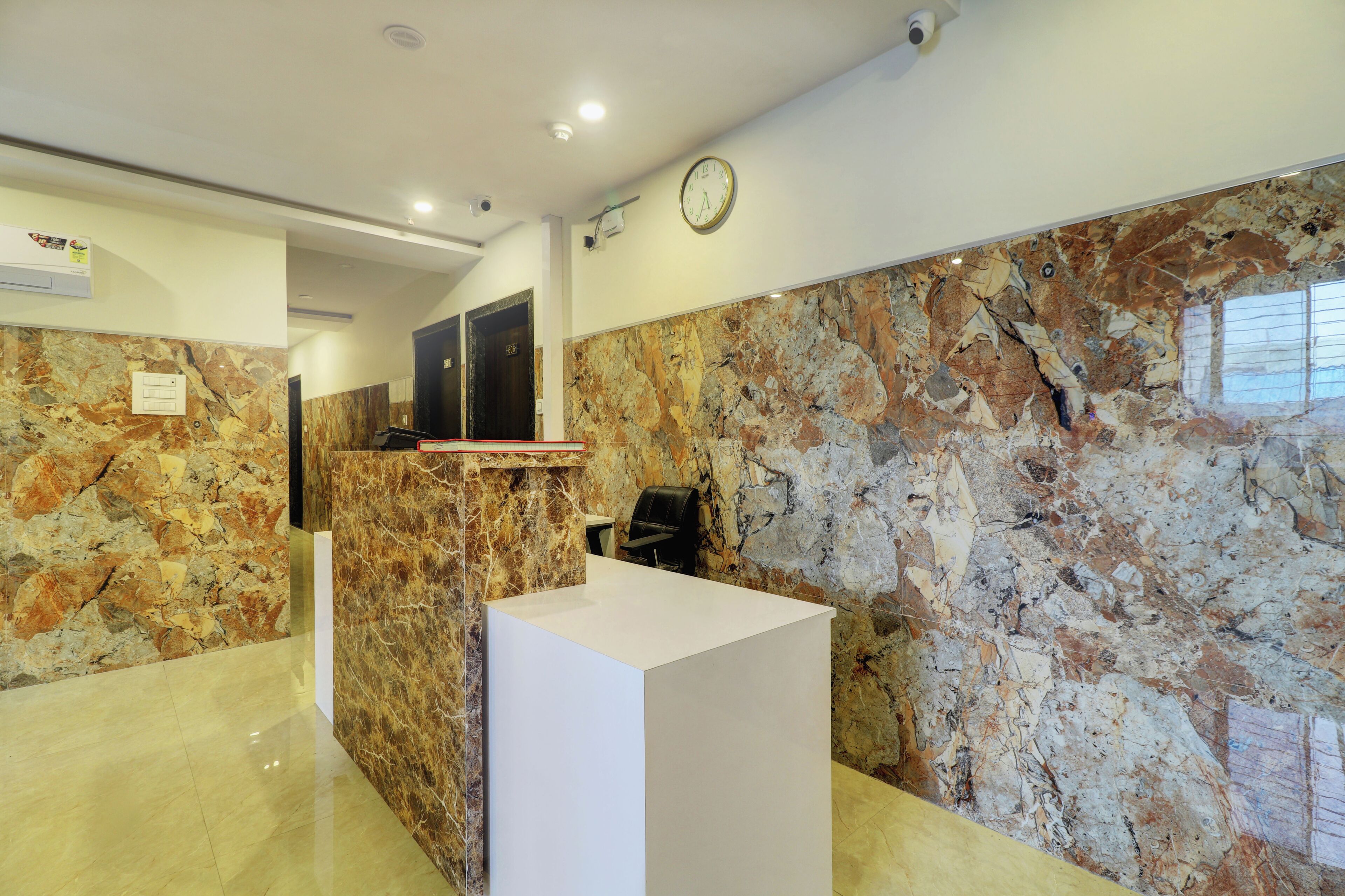 A reception area with a marble wall, a reception desk, and a clock on the wall.
