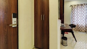 Une armoire en bois avec un petit appareil électronique fixé à la porte, une table à manger avec des chaises et un rideau à motifs.