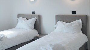 Two single beds with grey headboards and white bedding, each with a circular light fixture above. - Hotel Edelweiss Mantova (Castel d'Ario)