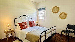 A bedroom with a bed, bedside tables, a chair, and a window.