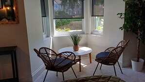 Een gezellig hoekje met twee rieten stoelen, een klein rond tafeltje en een potplant.