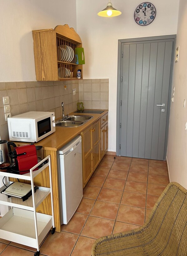 Una cocina compacta con microondas, lavabo y armarios de madera.