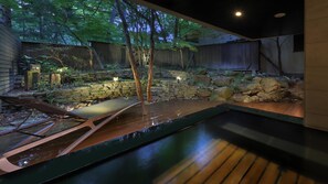 A modern outdoor patio with a pool, lounge chairs, and a stone wall. - KANOUYASHIMAONSEN (Nakanojo)