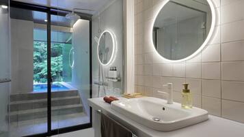 A modern bathroom with a glass shower enclosure, a large mirror, and a sink with toiletries.