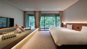A modern hotel room with a large bed, a television, and a balcony with a view of trees. - KANOUYASHIMAONSEN (Nakanojo)