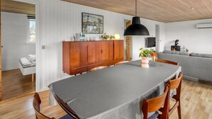 Un interior moderno con una mesa de comedor, armarios de madera, un sofá y una chimenea.