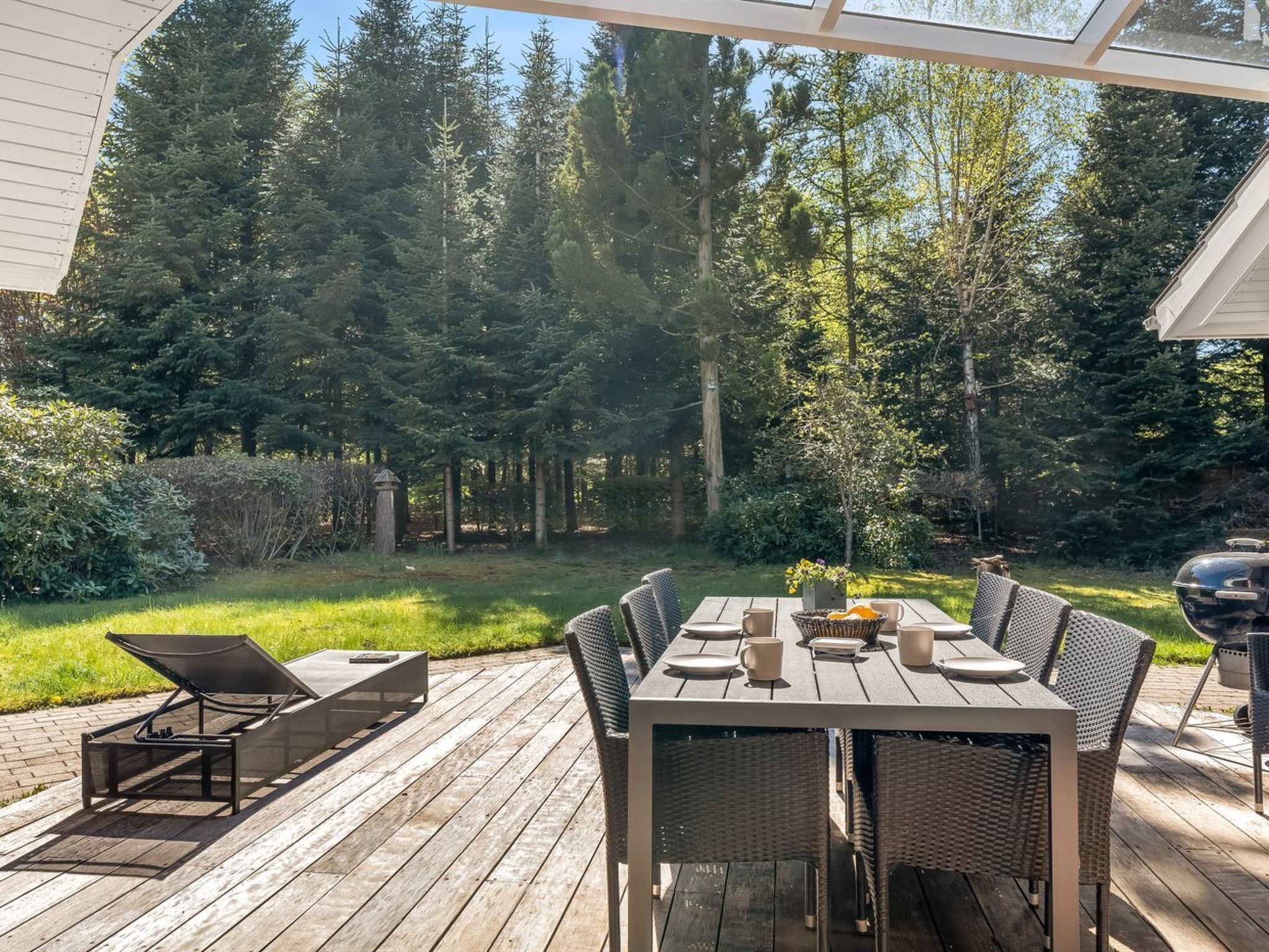An outdoor dining area with a wooden deck, wicker chairs, and a table set for four.