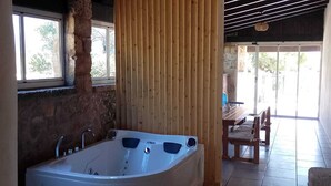 A bathroom with a stone wall, a wooden partition, and a large bathtub.