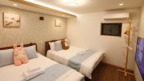 Habitación de hotel con dos camas, televisión, aire acondicionado y suelo de madera.