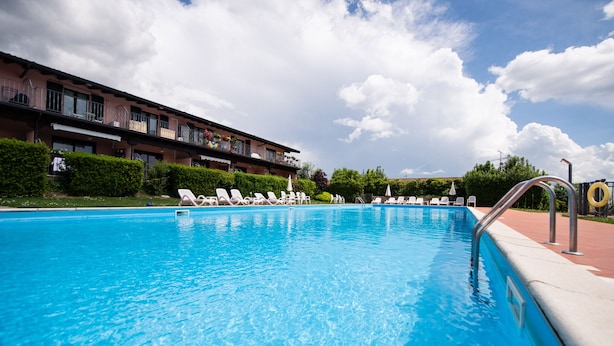 Una piscina con sillas de descanso y un edificio con balcones al fondo.