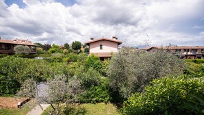 Zona residencial con una casa rosa rodeada de abundante vegetación y otras casas similares al fondo.