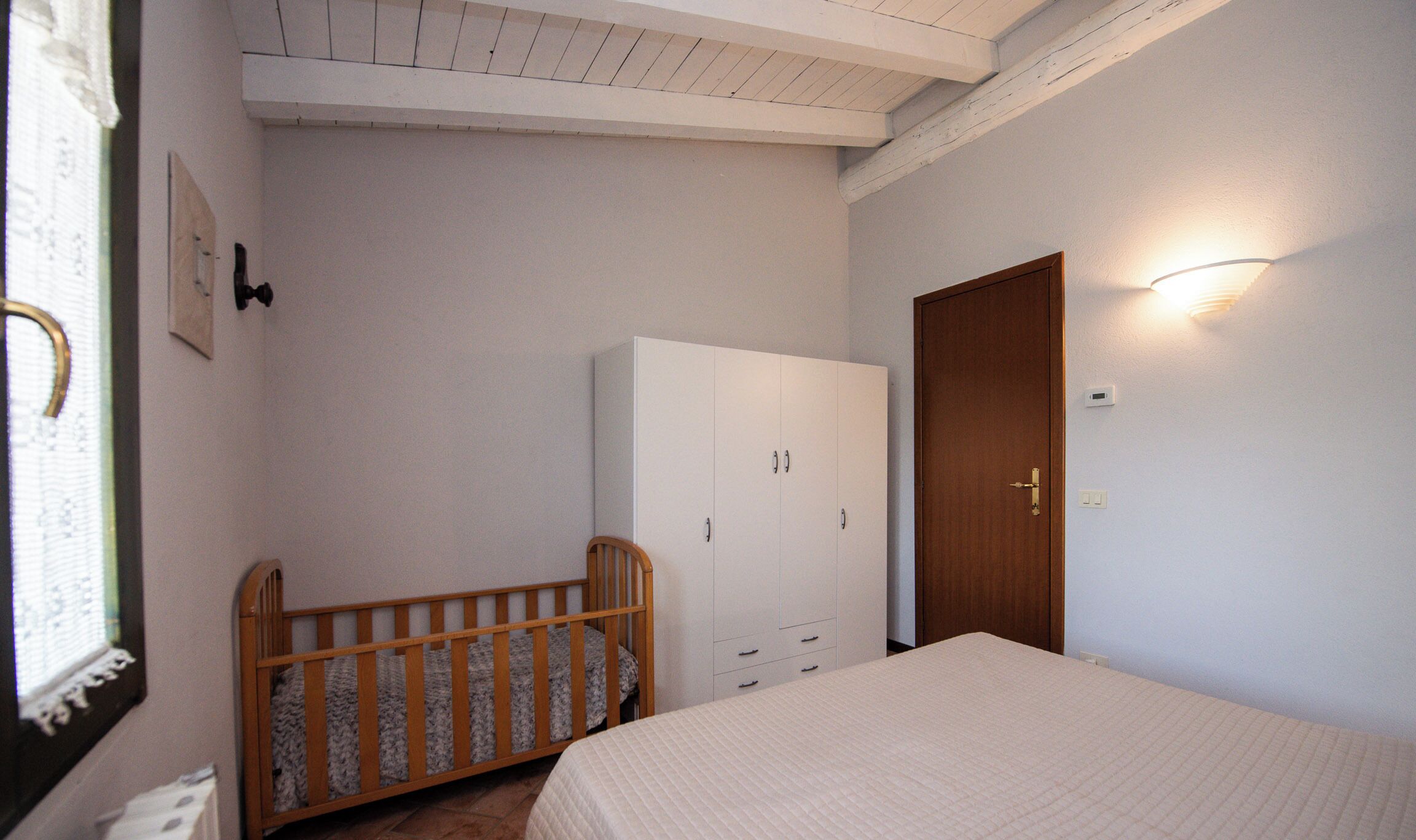 A bedroom with a crib, a wardrobe, and a door.