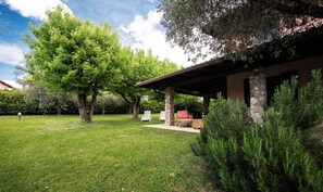 A well-maintained outdoor area with a stone building, a grassy lawn, and several trees.