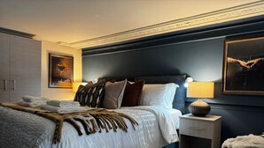 Une chambre d’hôtel moderne avec un grand lit, une table de chevet, une lampe et un tableau au mur.