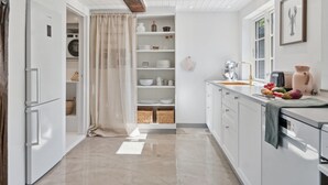 A modern kitchen with white cabinetry, a wooden ceiling beam, and a built-in washing machine.