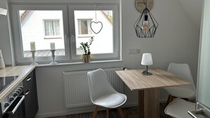 A modern kitchen with a dining area, featuring a white radiator, a wooden table, and a white chair.