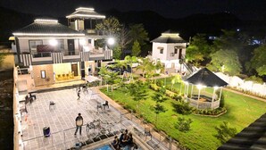 Un hotel con piscina, mobiliario exterior y un jardín bien iluminado.